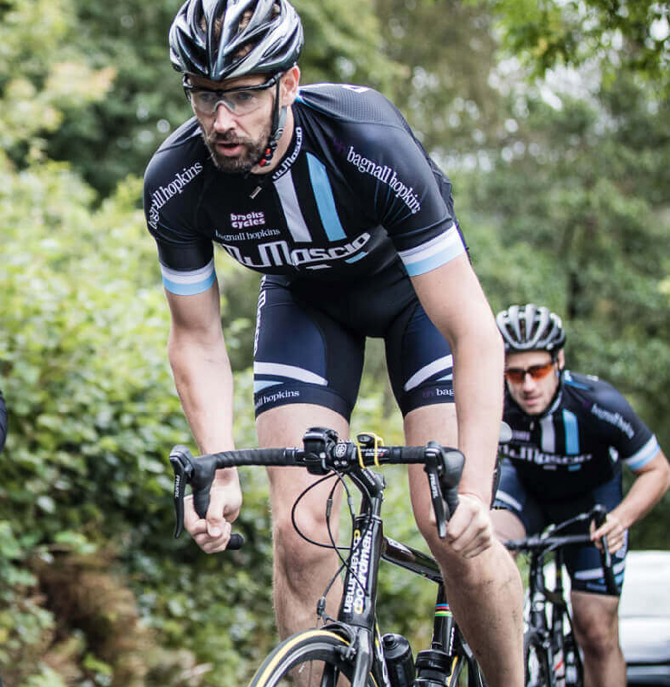 Cyclist riding up hill wearing Dimascio cycling clothing